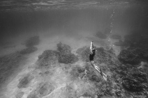 underwater photography of girl with coral