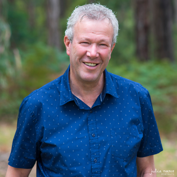 Smiling personal branding portrait of man outside wearing a blue shirt.