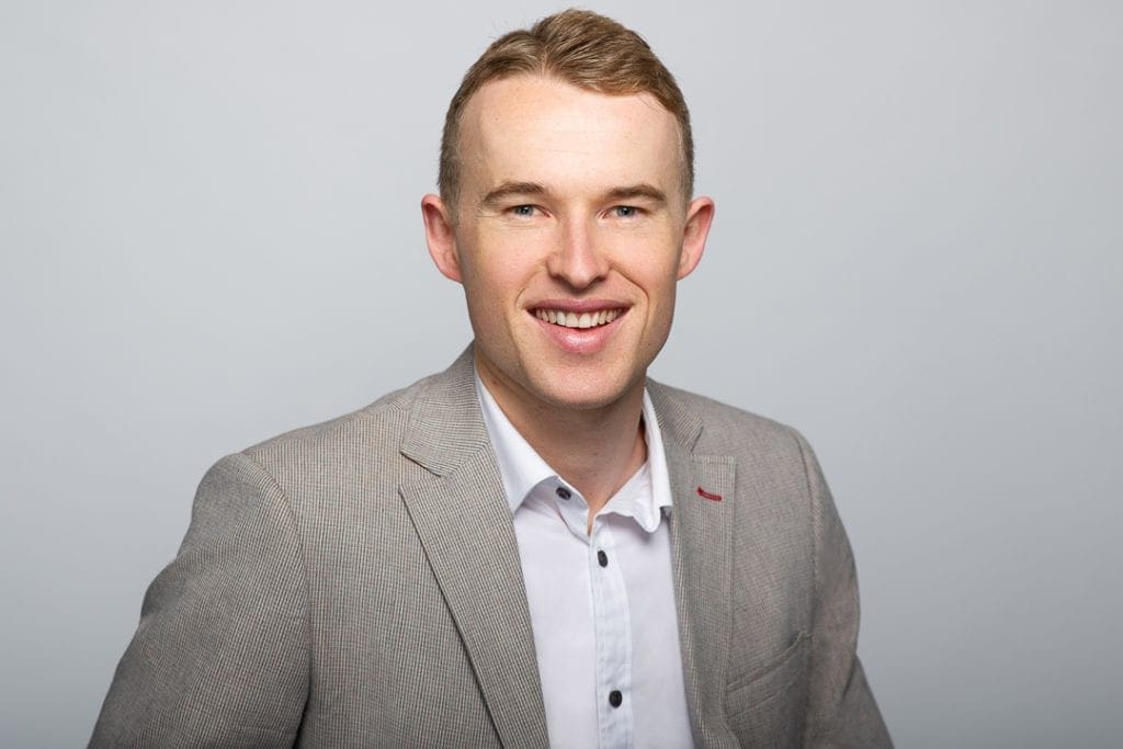 Melbourne corporate headshot of man smiling at camera on light grey background