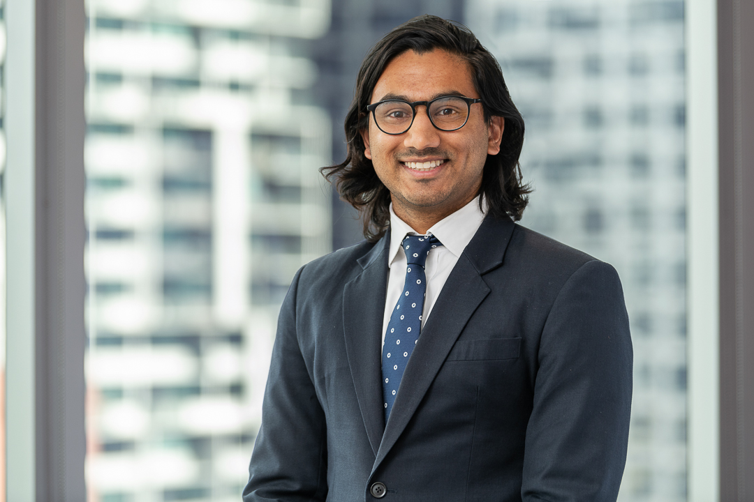 Corporate staff headshot of melbourne lawyer with city skyline background.