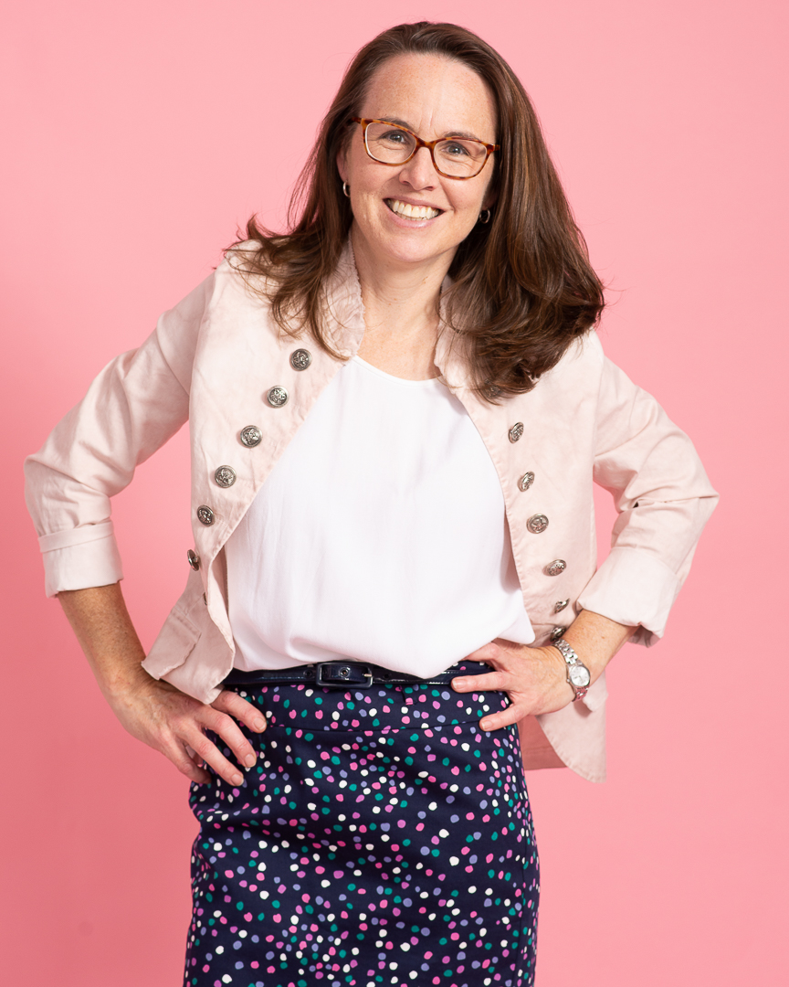 Woman poses with hands on hips and a smile for branding portrait.