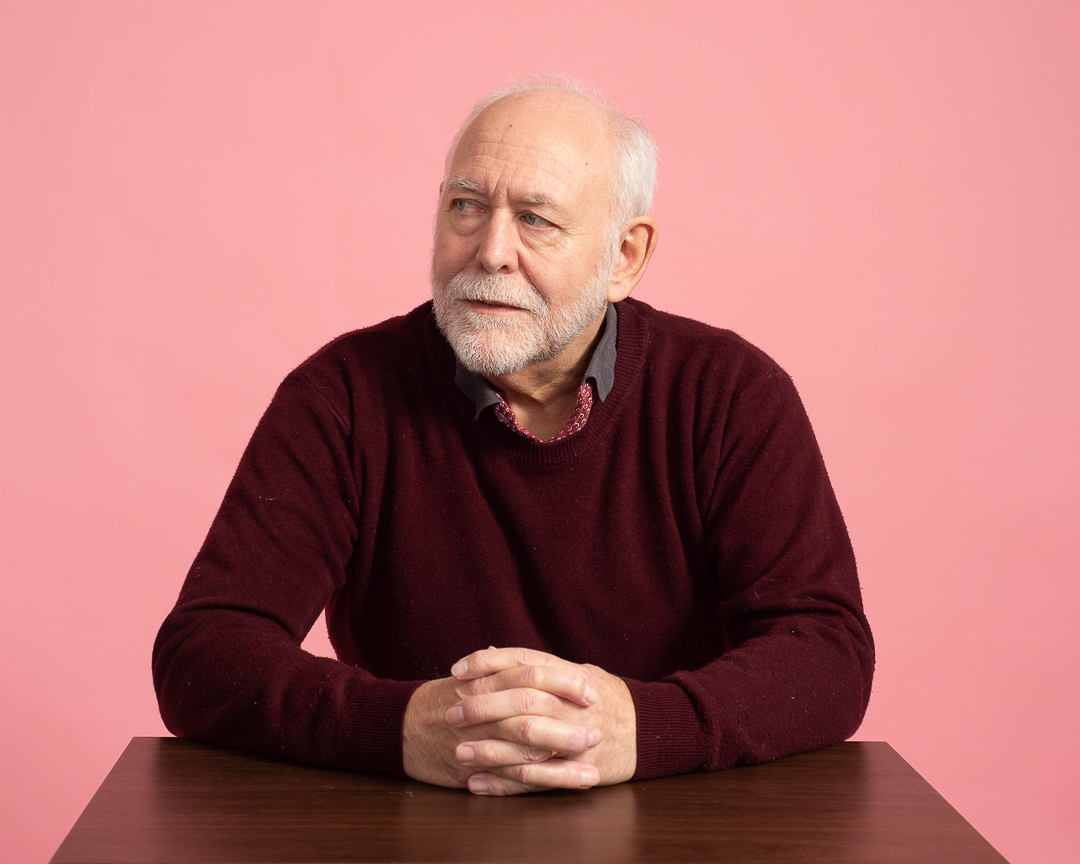 Man leans on a table looking away from camera for a studio personal branding portrait