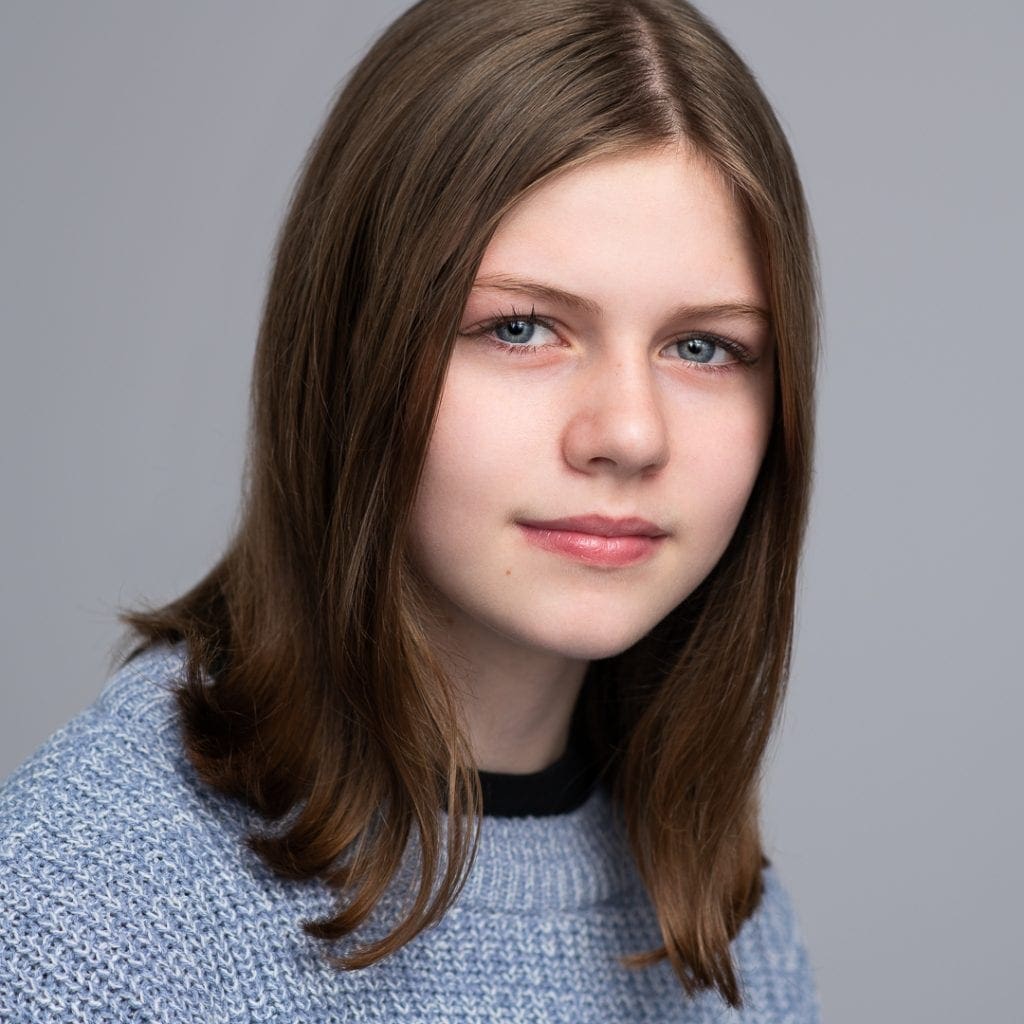 teen actor headshot image of girl in studio on a grey background.