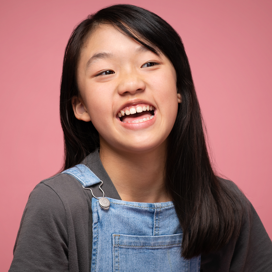 Candid actor headshot of teen girl laughing in studio.