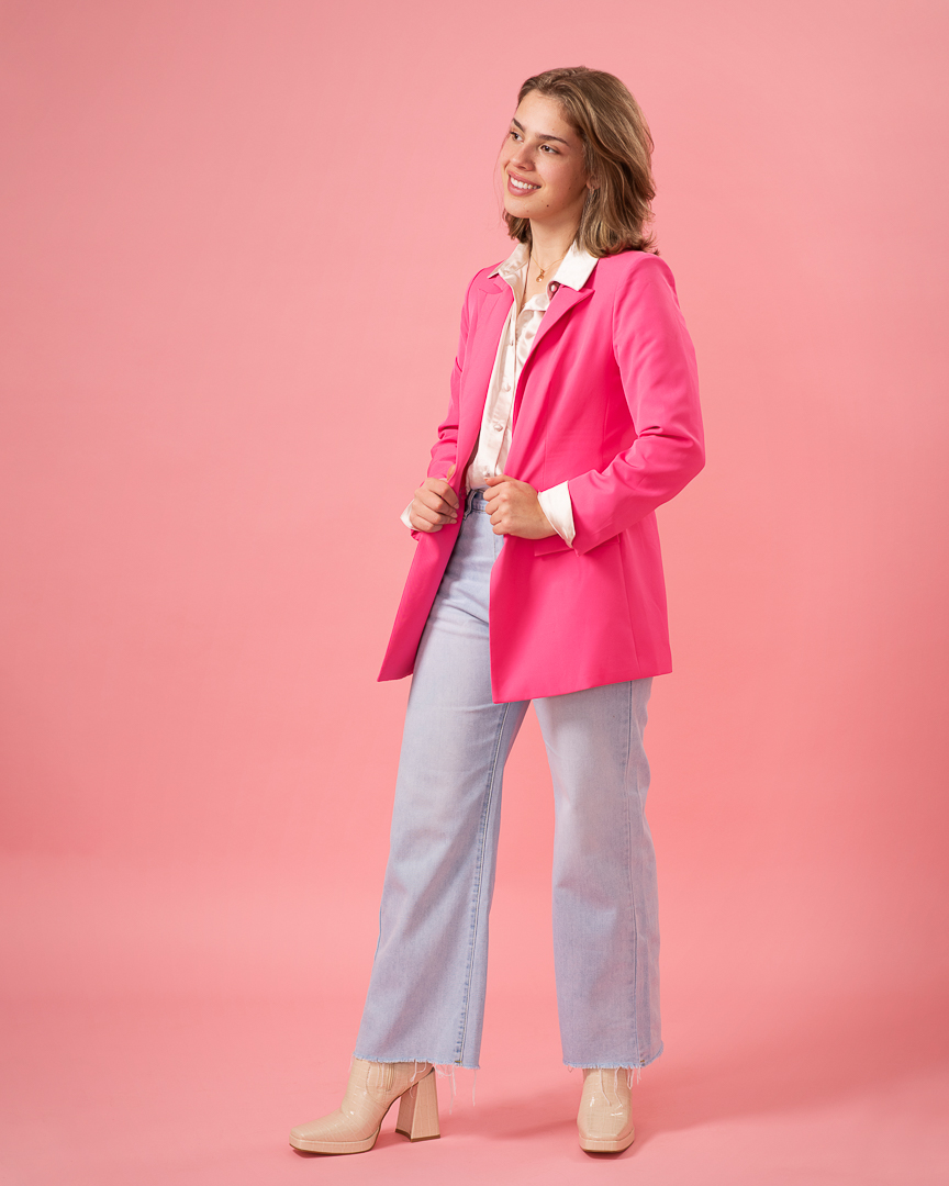 Melbourne actress poses in studio wearing a pink blazer in a confident stance.