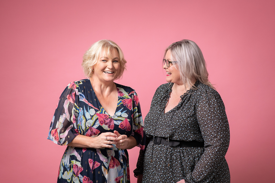 Podcaster duo Mandy and Kate laughing at each other in portrait taken for advertising campaign for podcast company Acast.
