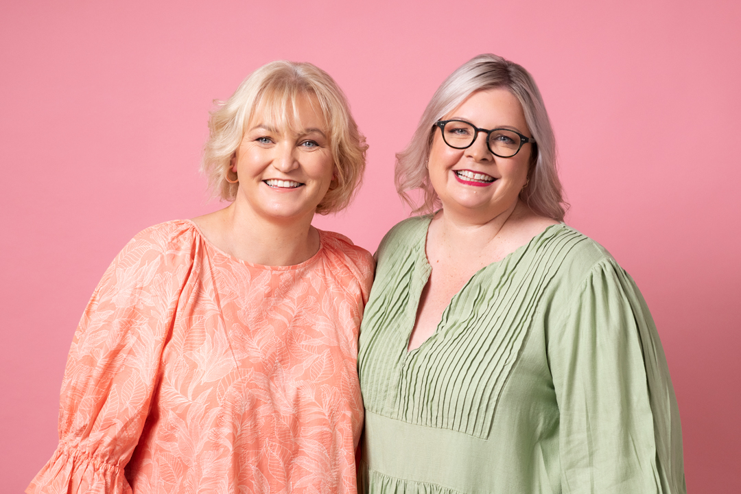 Podcaster duo Mandy and Kate smile to camera in portrait taken for advertising campaign for podcast company Acast.