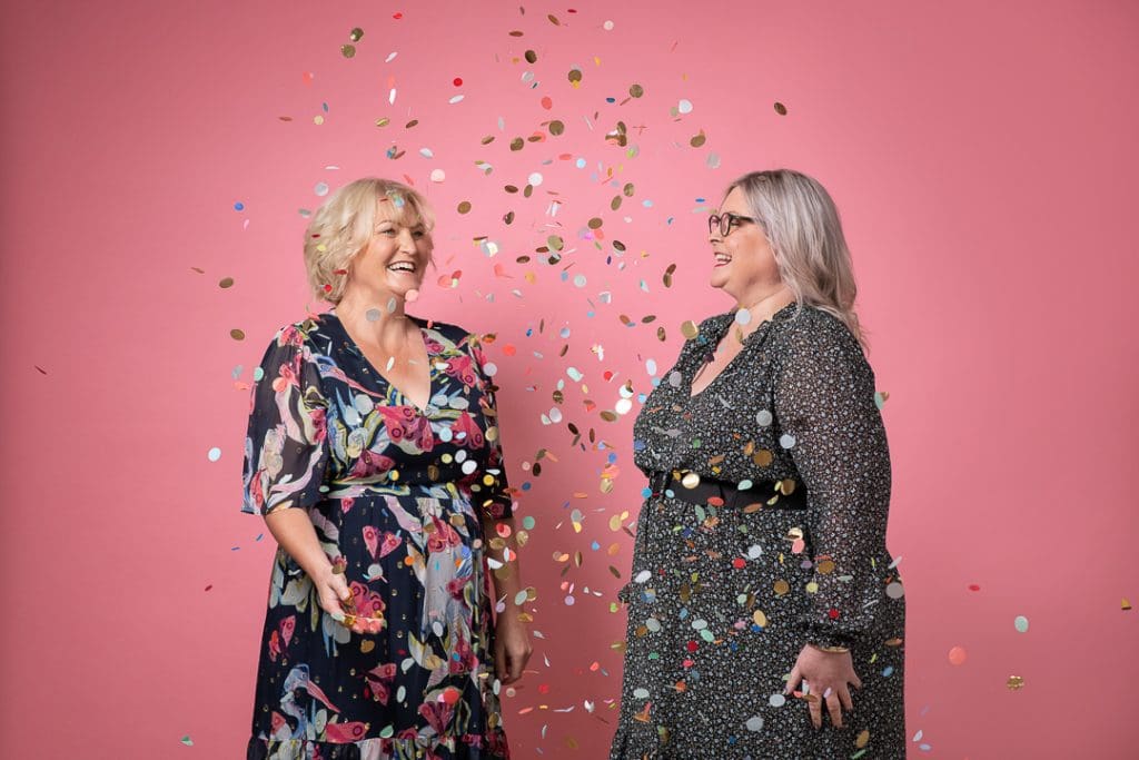Podcaster duo Mandy and Kate laugh while throwing confetti in personal branding photoshoot taken in Melbourne.