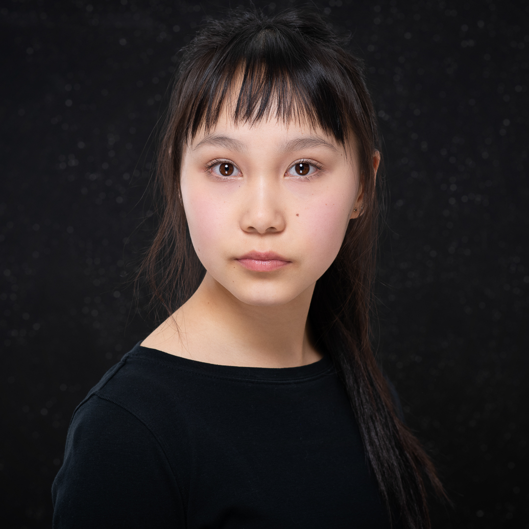 Studio headshot of Melbourne teen actress. The image has a black background and the model has a serious expression.