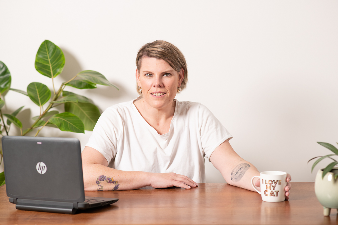 A relaxed lifestyle branding portrait of woman at a desk with her laptop and a cup of coffee,