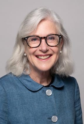 Melbourne barrister headshot of woman smiling to camera wearing a button up blue jacket and glasses.
