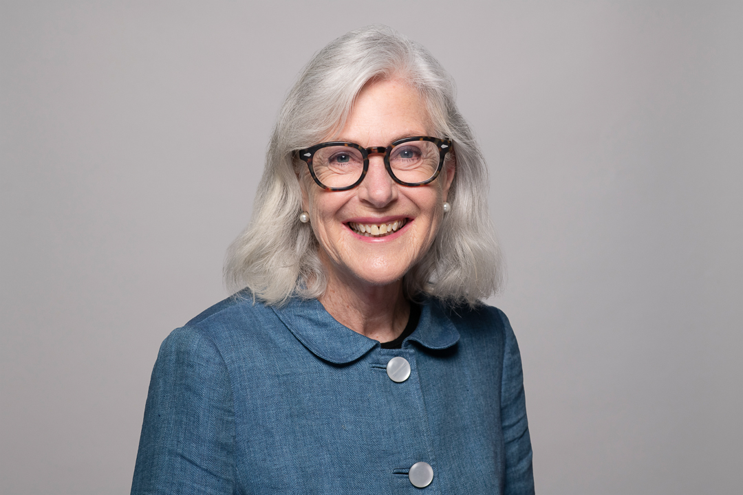 Melbourne barrister headshot of woman smiling to camera wearing a button up blue jacket and glasses.