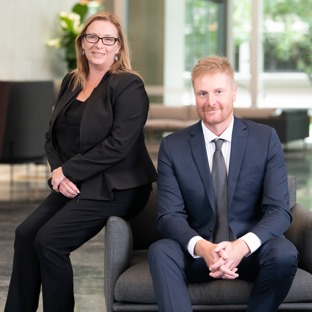 Corporate team photograph showing a woman and man - lawyers in a melbourne building foyer sitting professionally.