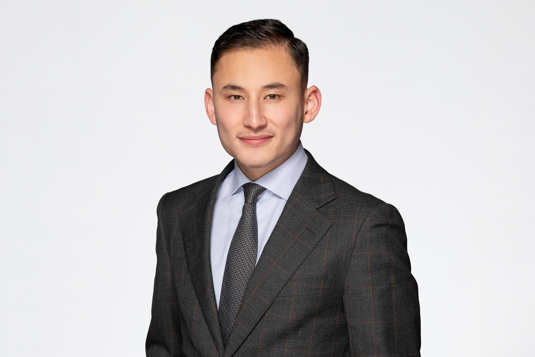 Melbourne barrister headshot of man wearing a grey suit with a tie, smiling to camera confidently.