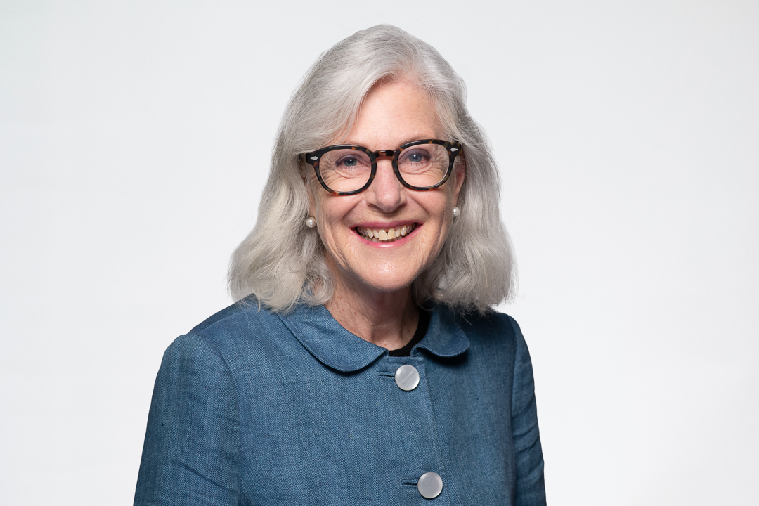 Melbourne barrister headshot of woman wearing a blue button up jacket and glasses, smiling to camera confidently.