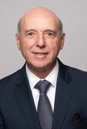 Melbourne LinkedIn headshot for local barrister, smiling to camera and wearing a navy suit and tie.