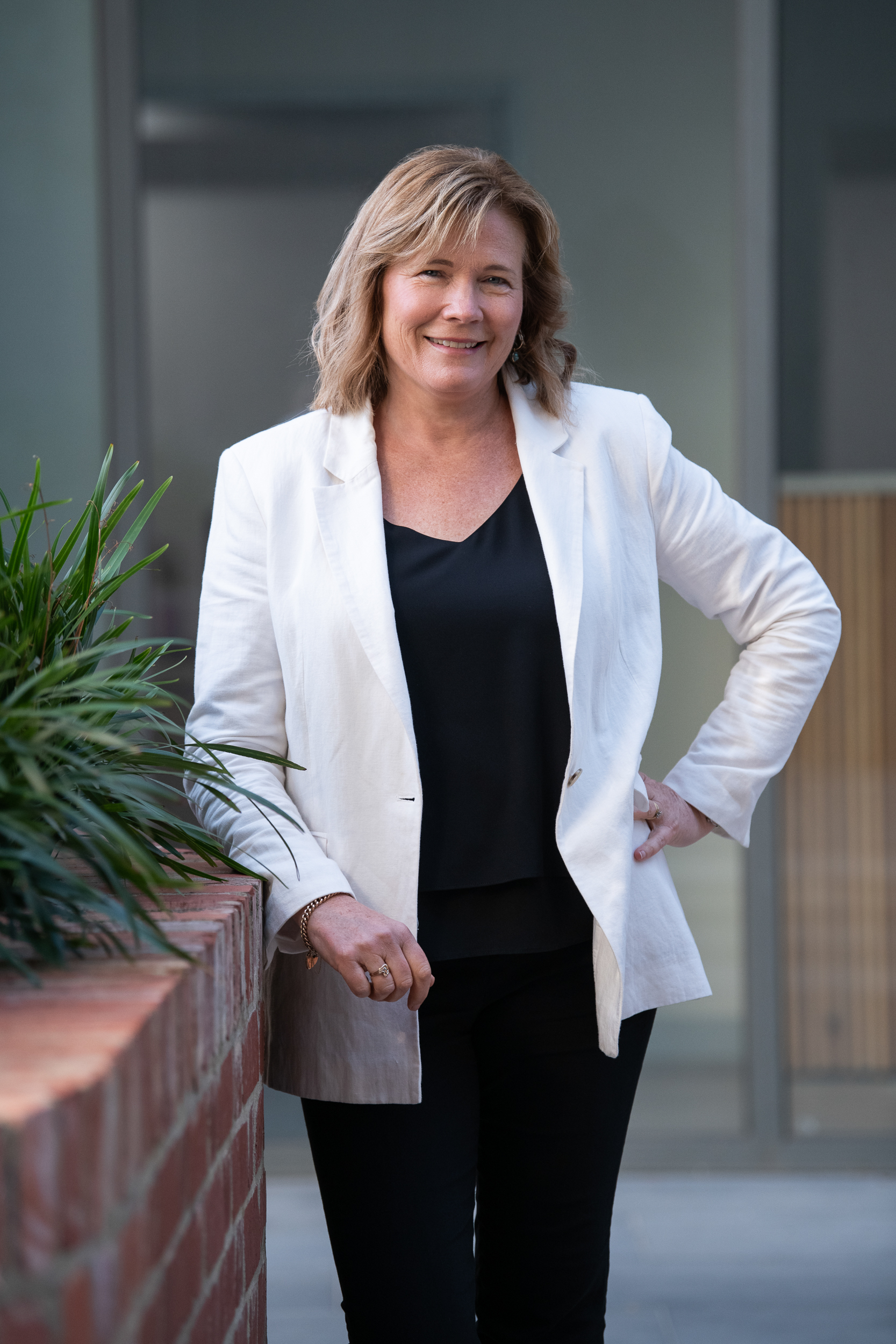 Personal branding portrait of Melbourne woman wearing white linen blazer, standing confidently with a smile.