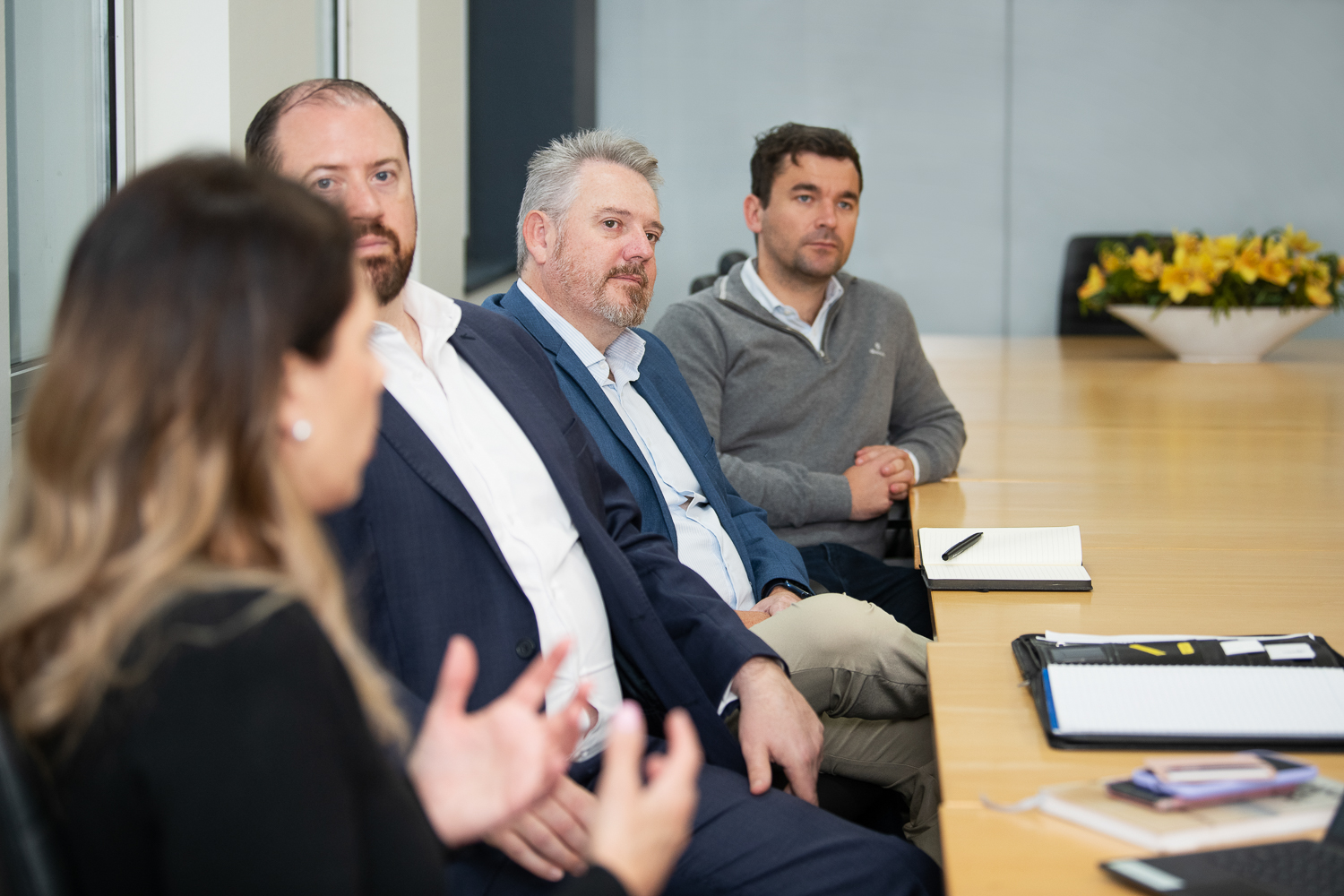 Personal branding photography of melbourne business - in-situ and working together in a collaborative way. Four staff members engage in a meeting at a large boardroom table.