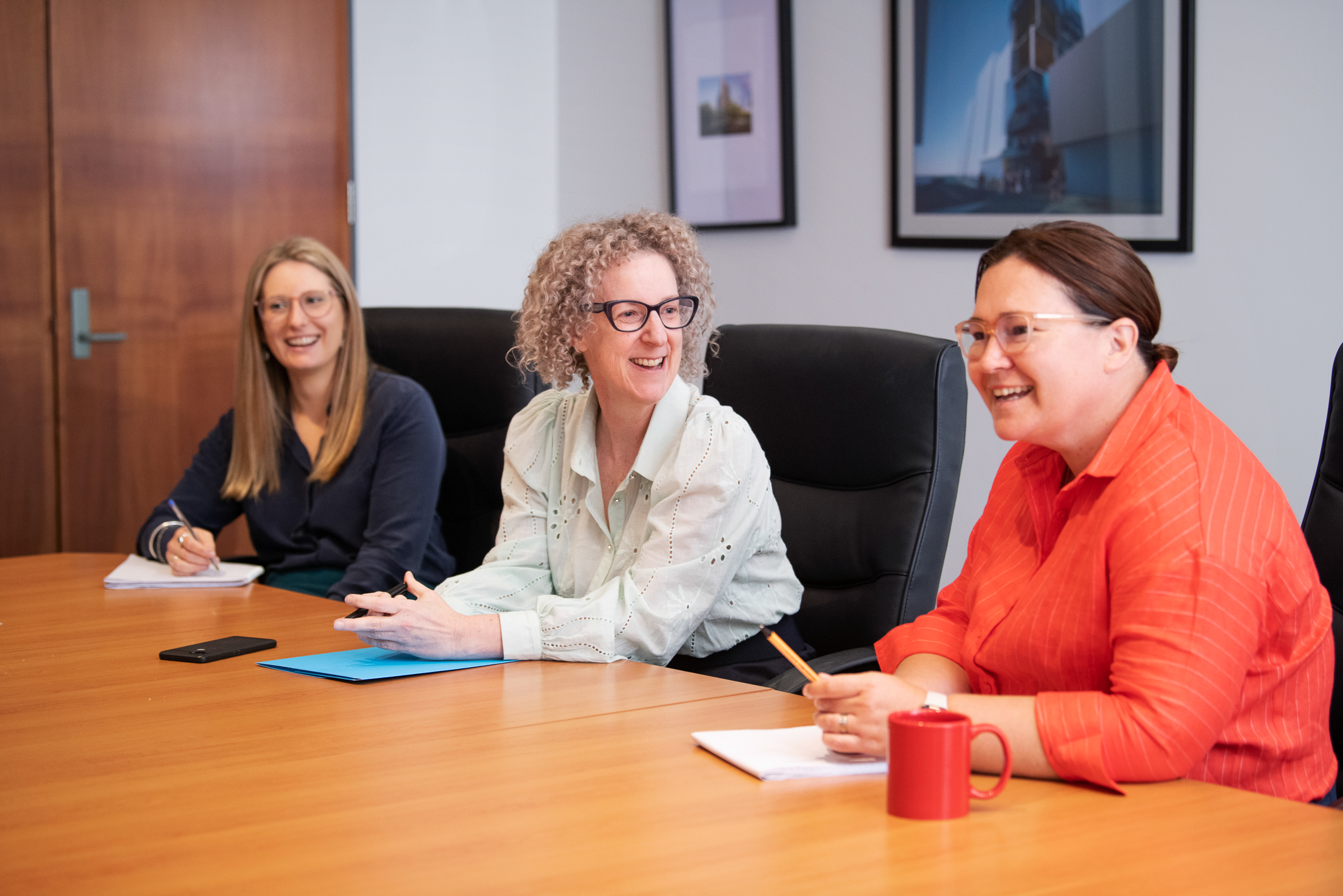 Melbourne team and staff photography. Personal branding group portraits of team collaborating and working together. Group of women smiling at each other in boardroom.